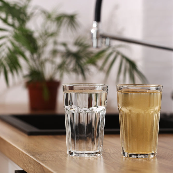 Clean water in a glass on left side and dirty brown water on the right side. Clean water is purified and cleaned by Reverse Osmosis